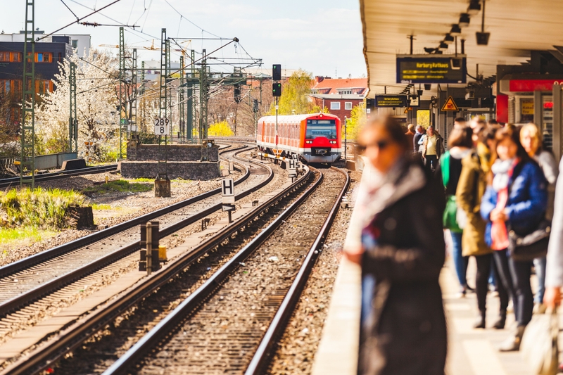 Menschen die am Bahnsteig stehen und auf einen Zug warten.